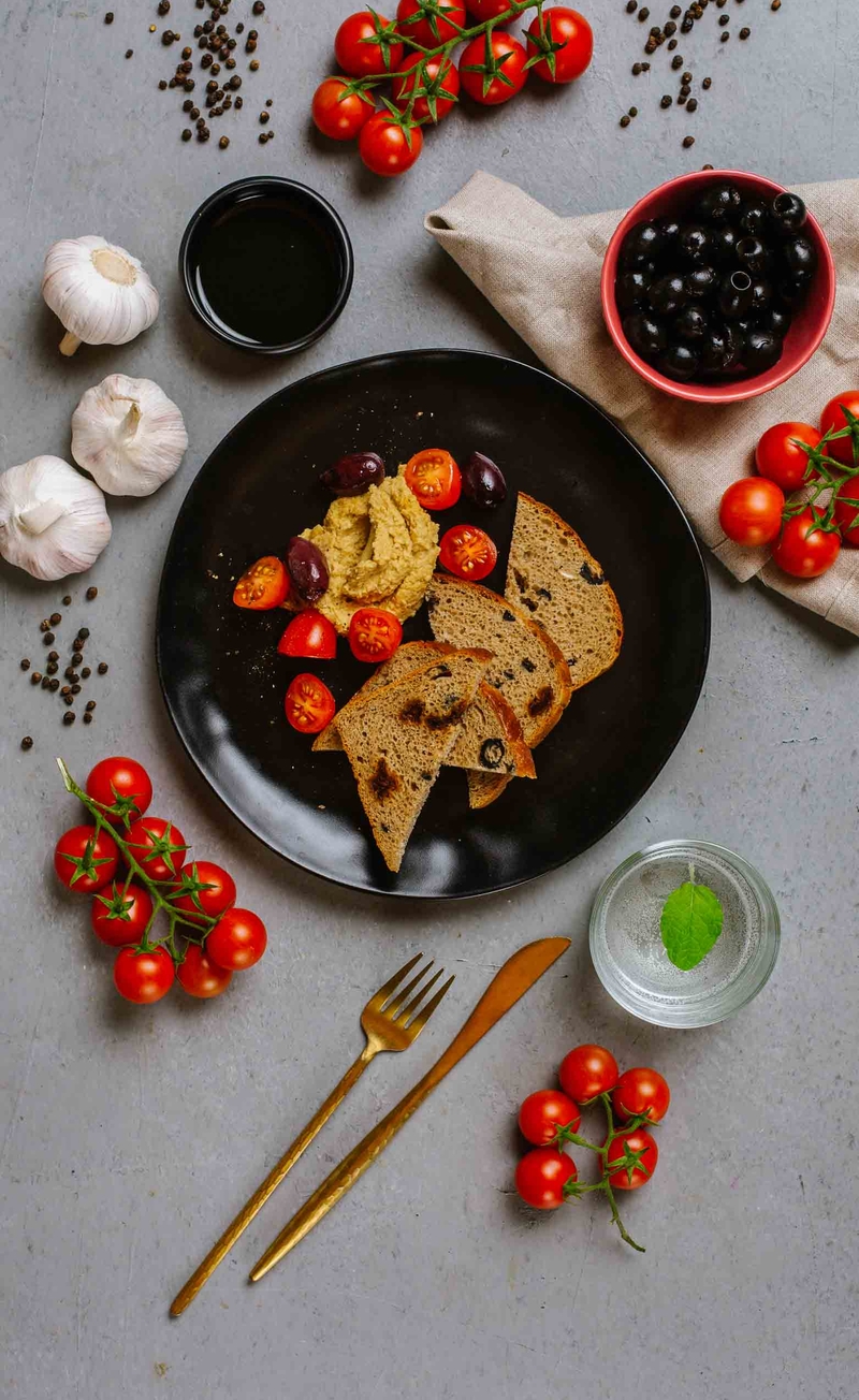 Hummus z tahini i oliwą z oliwek, chleb środziemnomorski, pomidorki, oliwki