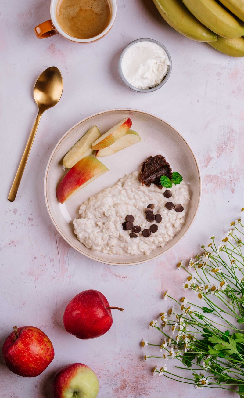 Proteinowa owsianka banoffee z gorzką czekoladą, bita śmietana bez cukru, cząstki jabłka