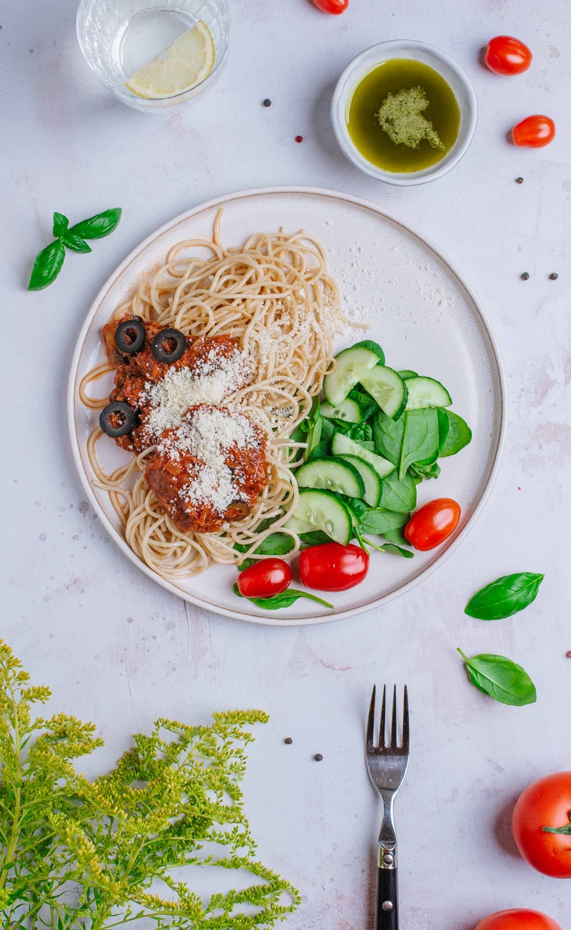 Pełnoziarniste spaghetti w sosie pomidorowym z tuńczykiem i czarnymi oliwkami, świeże warzywa, bazyliowy winegret