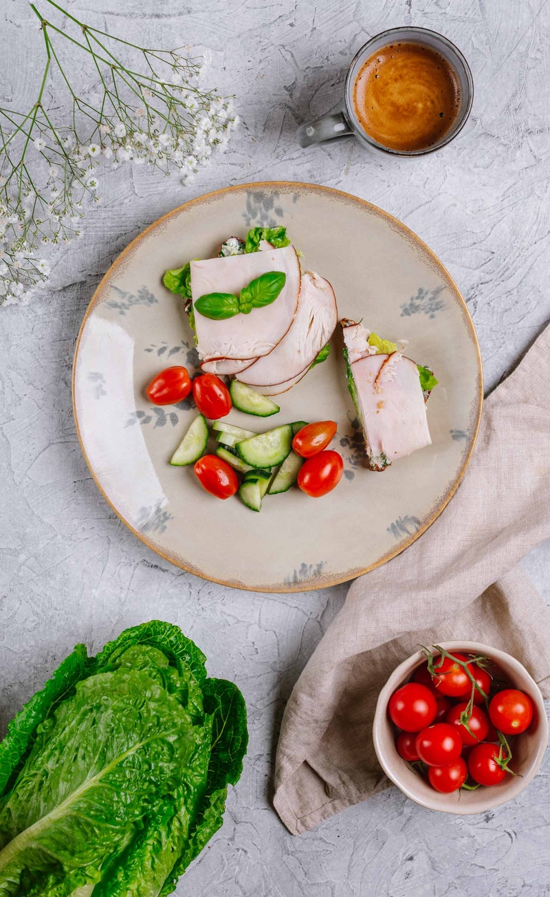 Proteinowa kanapka na żytnim pieczywie z masełkiem ziołowym, szynką i sałatą, świeże warzywa