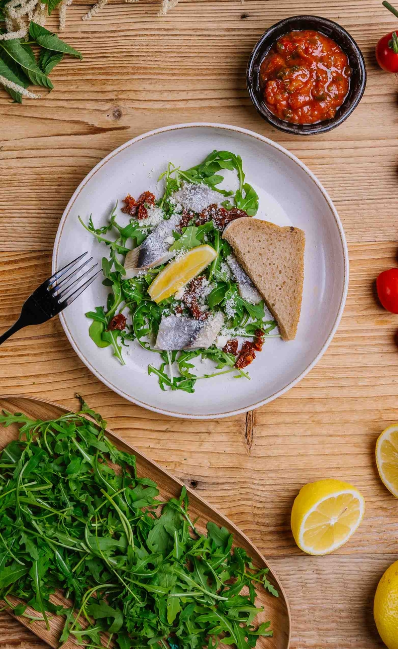 Śledź w salsie z pomidorów i ostrej papryki z rukolą, parmezanem i cytryną, chleb żytni