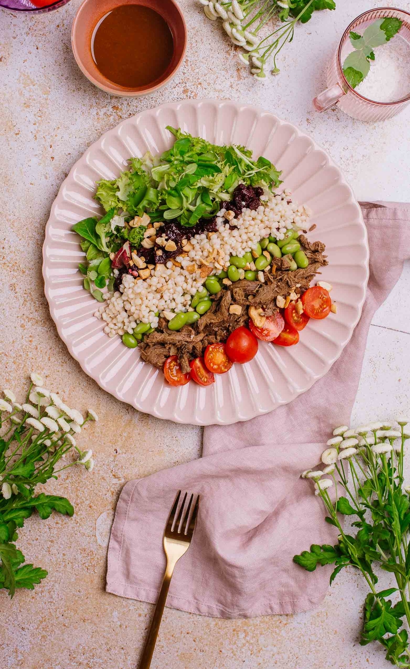 Buddha bowl z wołowiną, kuskusem perłowym, edamame, burakiem i mixem sałat, nerkowce, sos sojowo-sezamowy