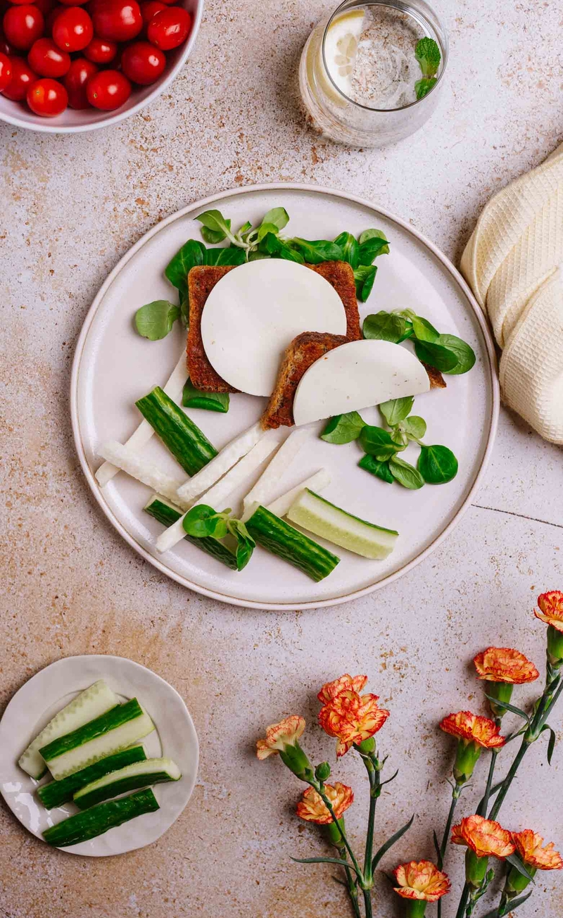 Razowa kanapka z serkiem Capri, pomidorowym pesto i roszponką, słupki ogórka i kalarepy
