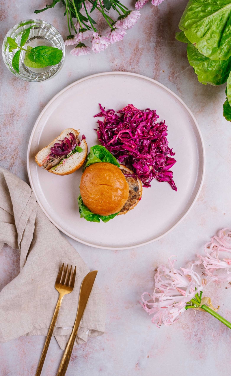 Różowy burger z sałatą rzymską, czerwoną cebulą i pink mayo, surówka z czerwonej kapusty