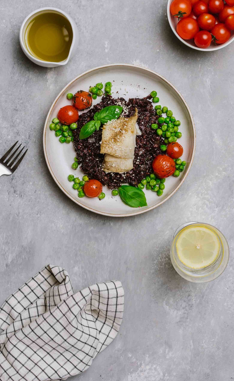 Dorsz na czarnym risotto, pieczone pomidorki z groszkiem, olej porowy