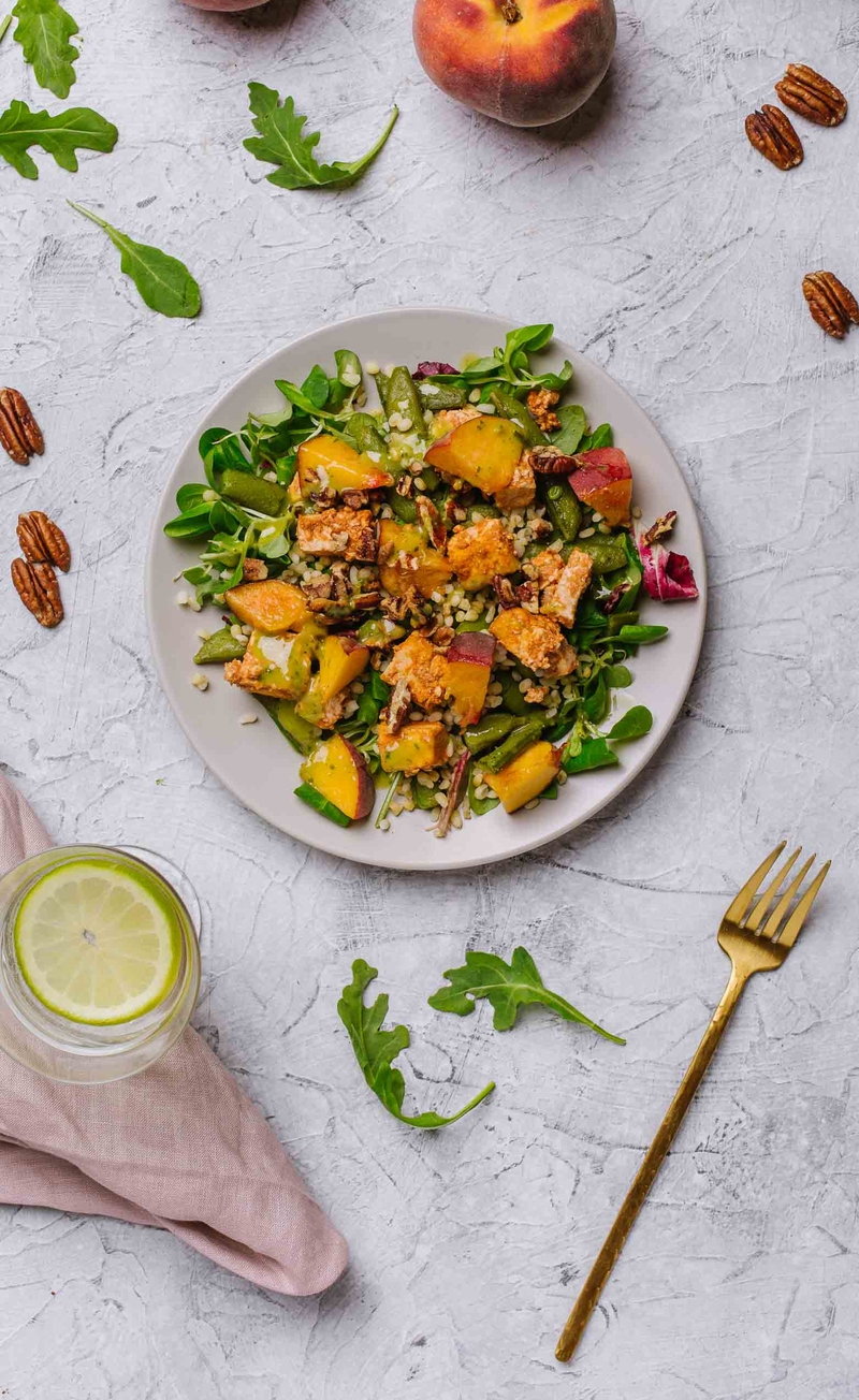 Mix sałat z groszkiem cukrowym, brzoskwinią, orzechami pekan, marynowanym tofu  i kaszą bulgur, dressing bazyliowy