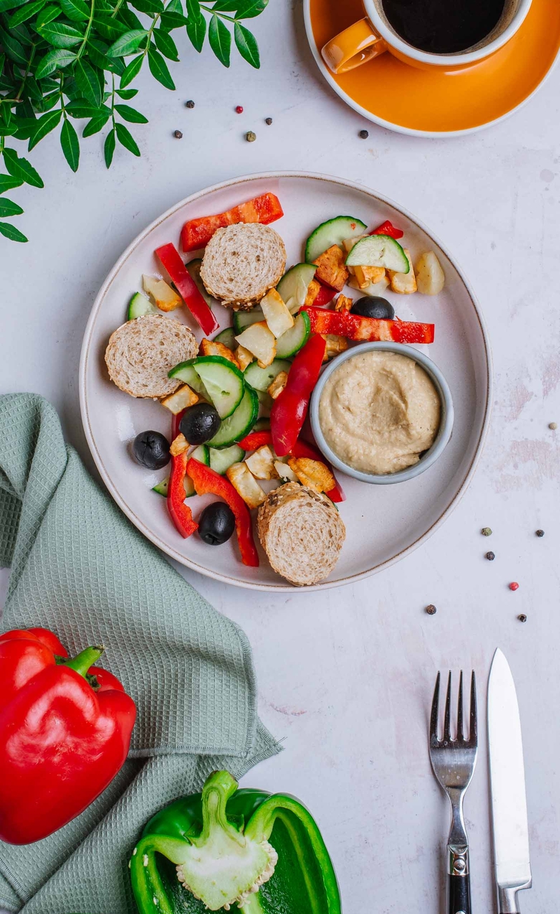 Śniadaniowy bowl z pieczonym halloumi, papryką, ogórkiem i oliwkami, hummus, bagietka graham