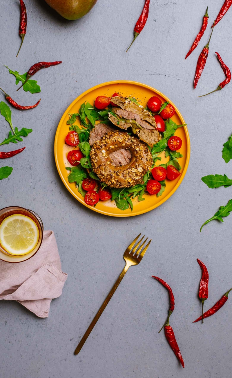 Bajgiel z plastrami wołowiny, rukolą i piklowanym pikantnym ogórkiem, sos mango-chili, pomidorki