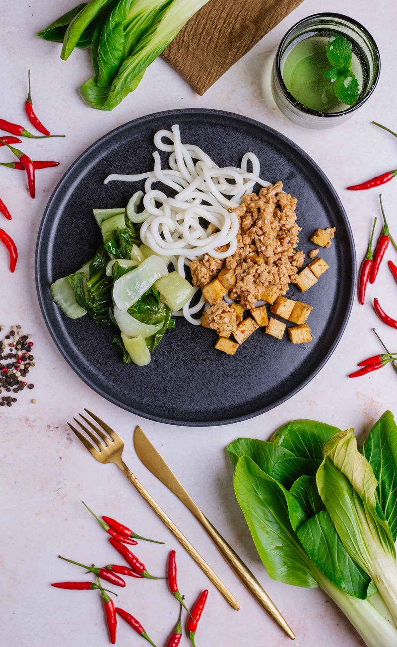 Dan dan udon z tofu, nie-mięsem i pikantnym sosem sezamowym, parowane liście kapusty pak choi