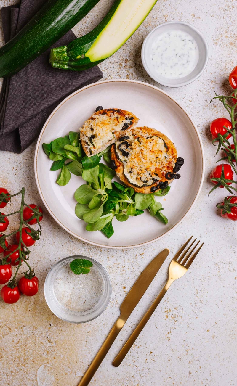 Pełnoziarnista pizza z sosem pomidorowym bez cukru, halloumi, oliwkami i cukinią, sos jogurtowo-czosnkowy