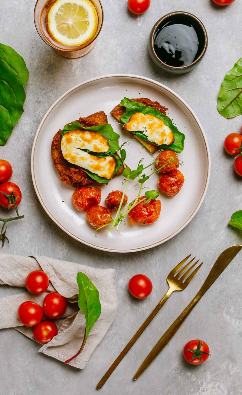 Tostowana brioszka z pesto rosso, pieczonym halloumi i świeżymi listkami, pieczone pomidorki z balsamico