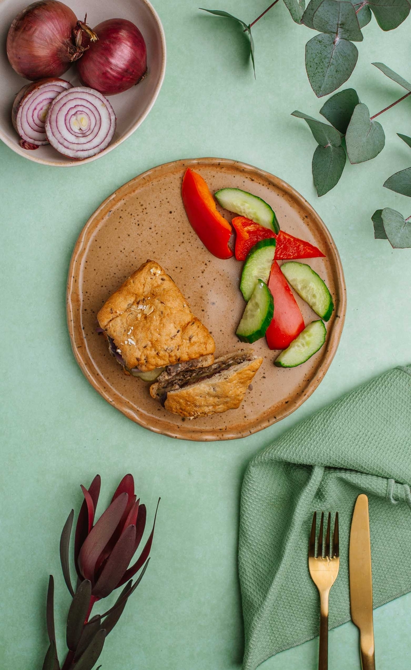 Burger owsiany z roślinną kaszanką, ogórkiem konserwowym i marynowaną czerwoną cebulką, świeże warzywa