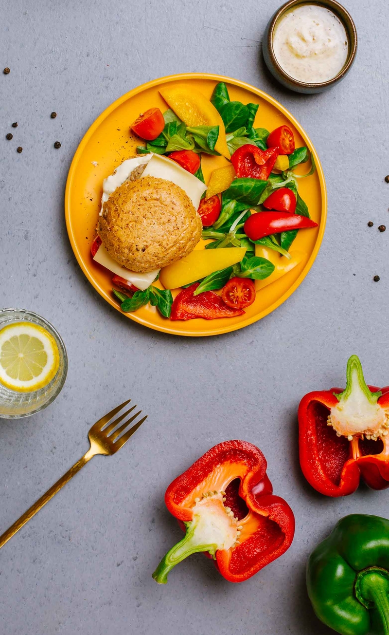 Drobiowy burger w grahamce z serem edamskim i sosem musztardowo-majonezowym, świeże warzywa