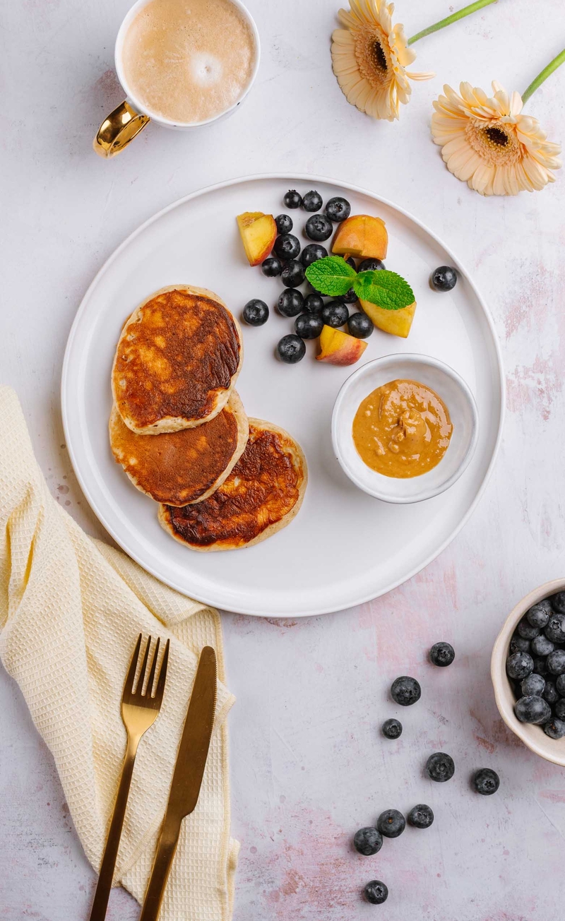 Proteinowe pancakes, wysokobiałkowy krem migdałowy, brzoskwinia, borówki