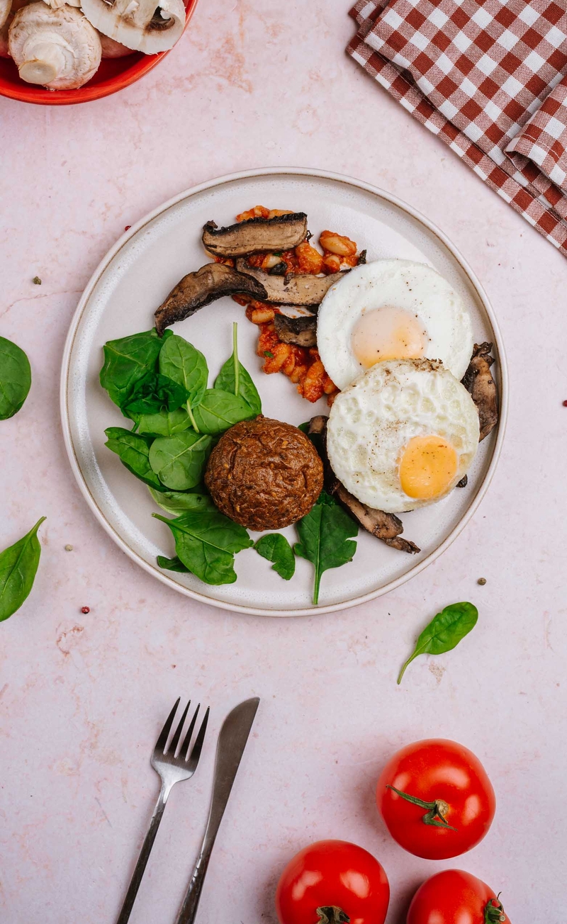 Wegetariańskie English breakfast z jajkiem sadzonym, fasolką w sosie pomidorowym, pieczonymi pieczarkami, bułeczka proteinowa