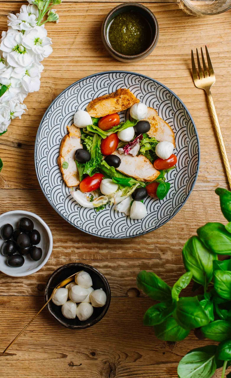 Sałatka keto antipasti z mini mozzarellą, oliwkami, plastrami kurczaka i mixem sałat, bazyliowy pesto-dressing