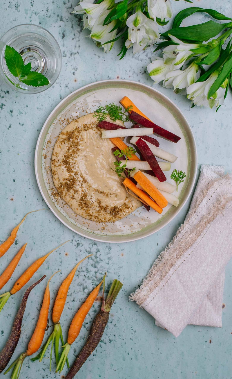 Kremowy hummus z oliwą z oliwek i za'atarem, świeże słupki warzyw