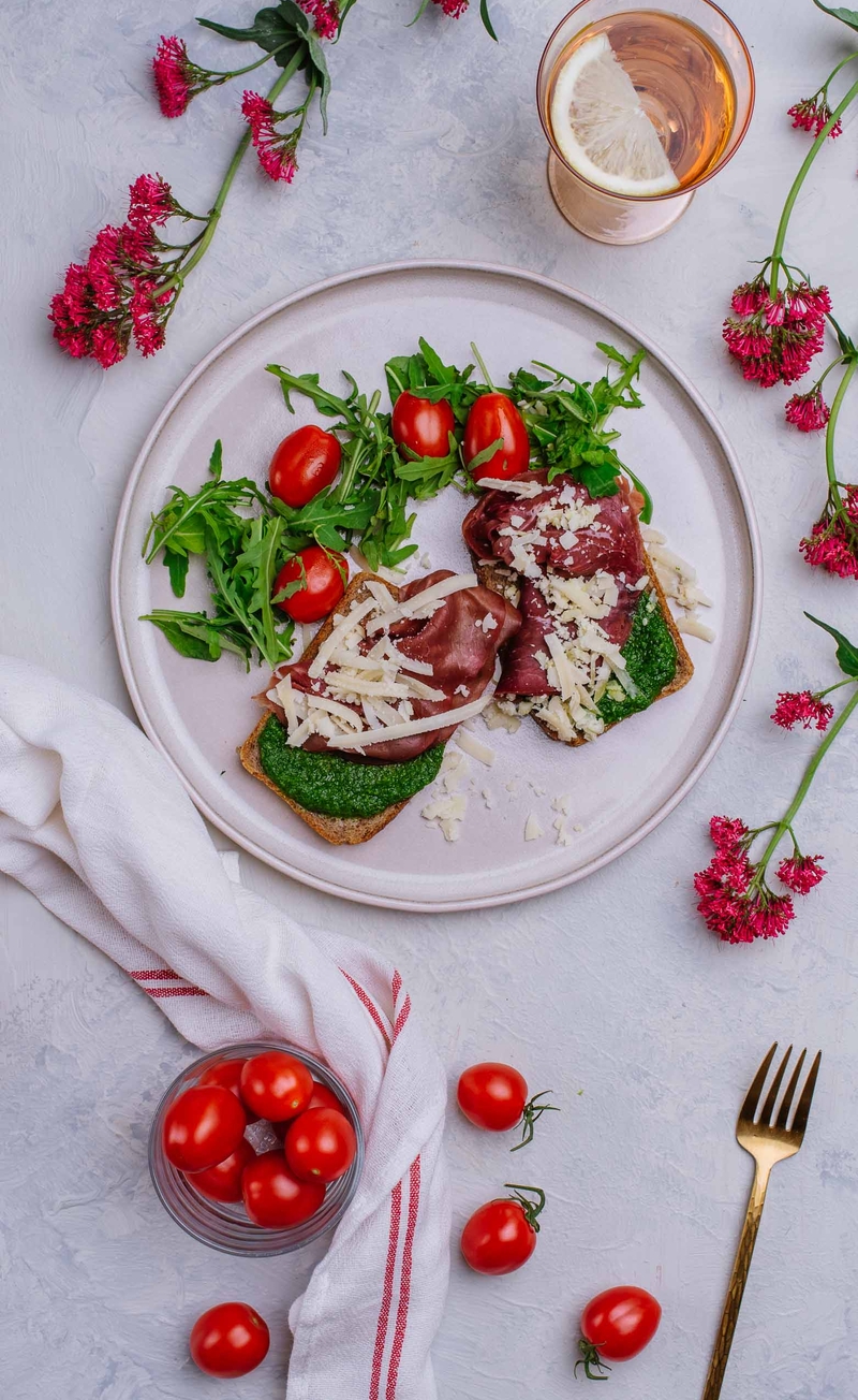 Kanapka razowa z pesto z rukoli, szynką bresaola i grana padano, pomidorki koktajlowe