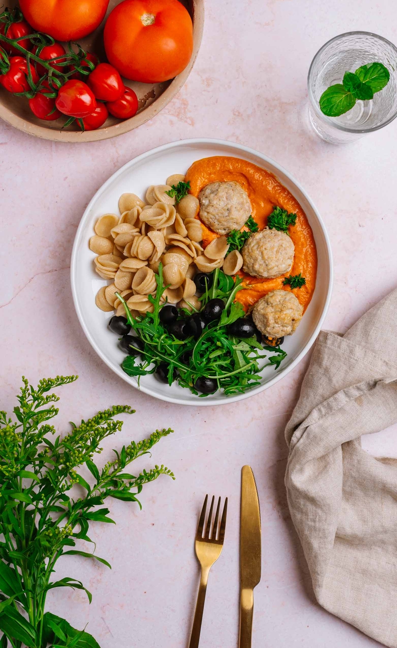 Pełnoziarnisty makaron orecchiette w kremowym sosie pomidorowym z drobiowymi pulpecikami, rukola i czarne oliwki