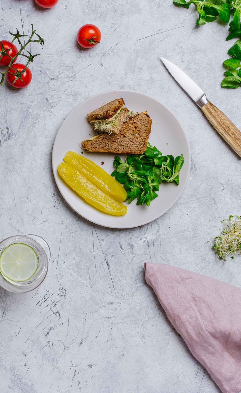 Kanapka razowa z pomidorowym pesto, roszponką i żółtym serem, pikle z ogórków