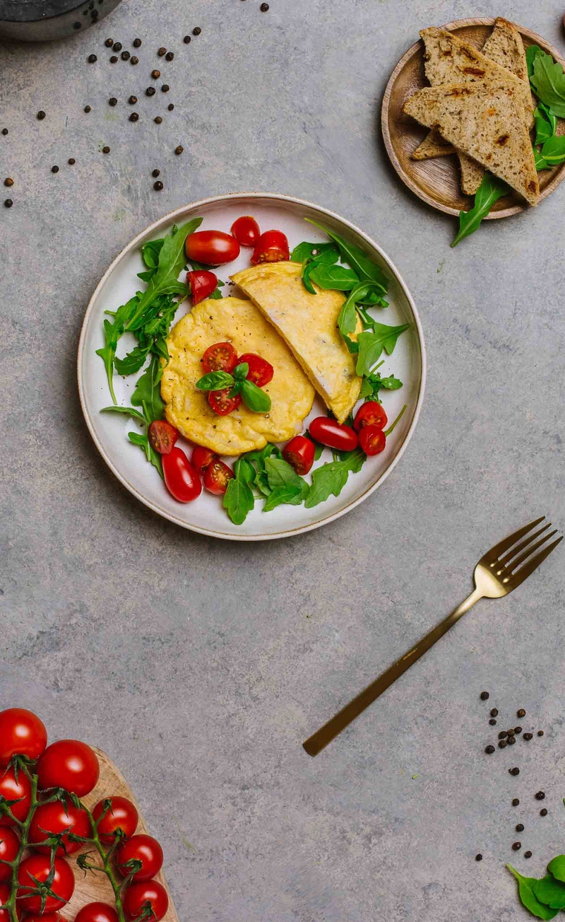 Omlet z mozzarellą, szynką z indyka i rukolą, chleb włoski z oliwkami, pomidorki