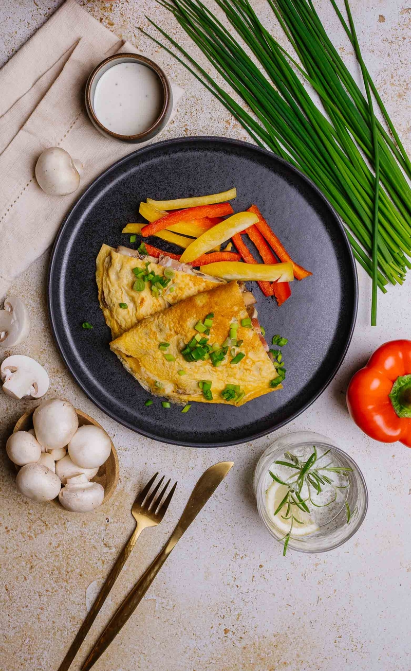 Omlet z duszonymi pieczarkami, speckiem i szczypiorkiem, sos jogurtowo-majonezowy, słupki papryki