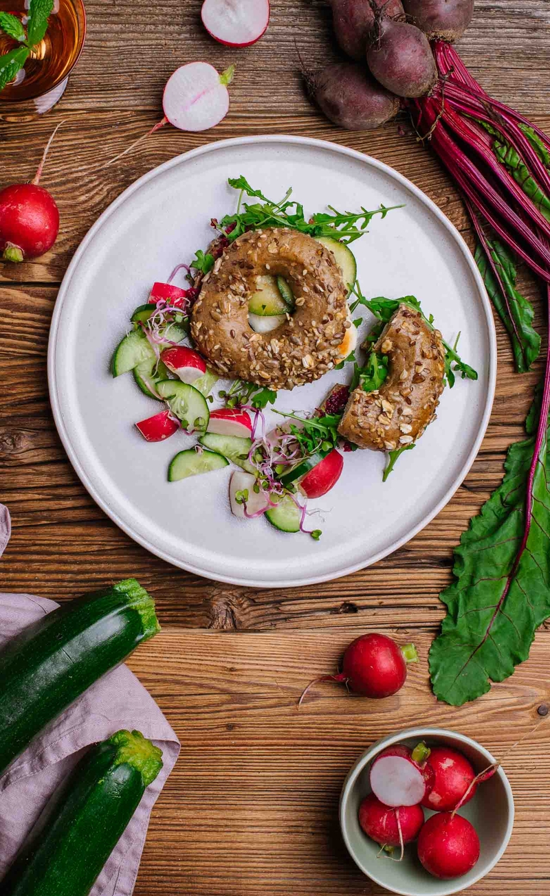 Bajgiel z pieczonymi plastrami cukinii, pesto z botwinki i serem halloumi, świeże warzywa
