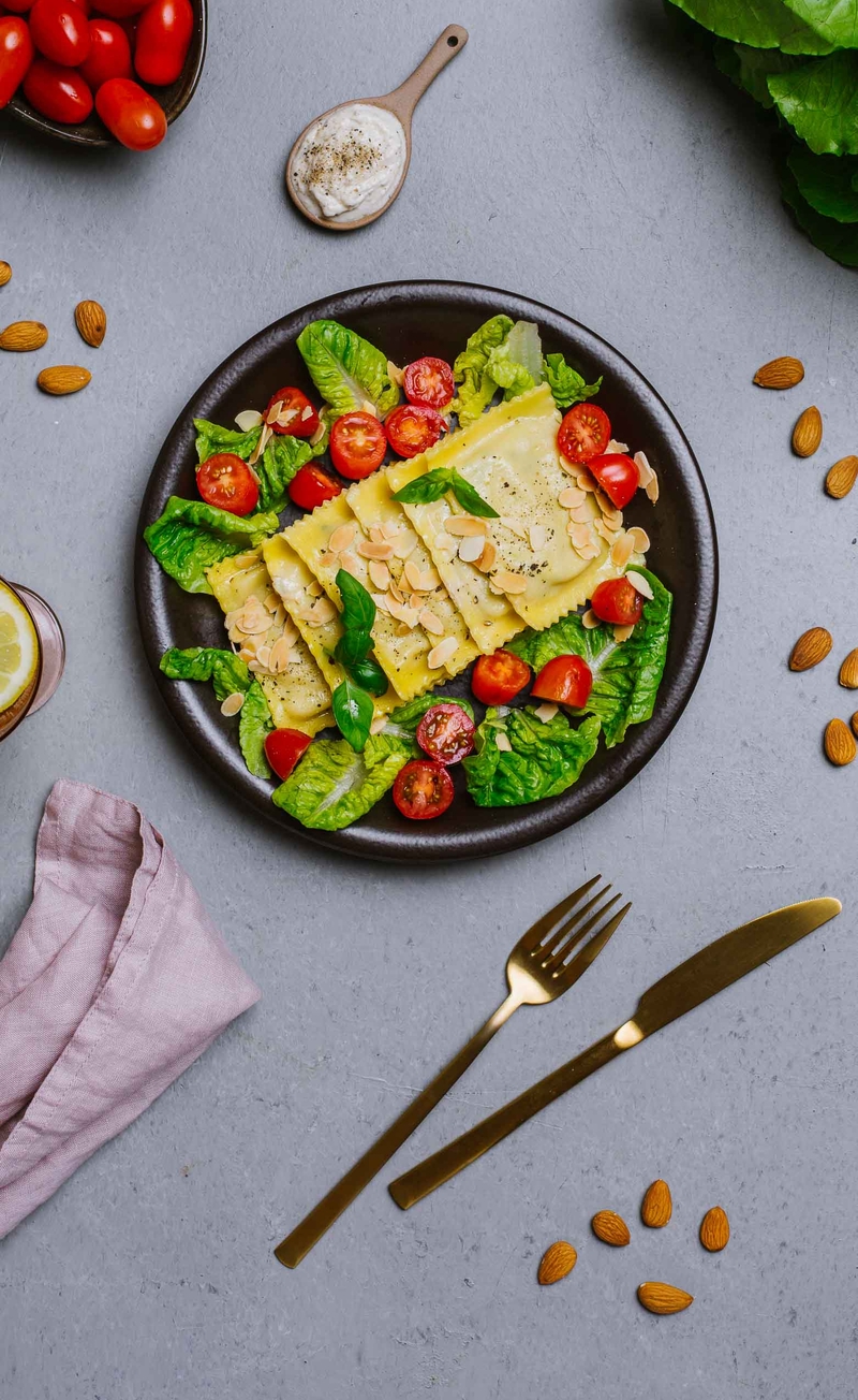 Ravioloni ze szparagami i mascarpone w śmietankowym sosie z pecorino i świeżym pieprzem, sałata rzymska z pomidorkami i prażonymi migdałami