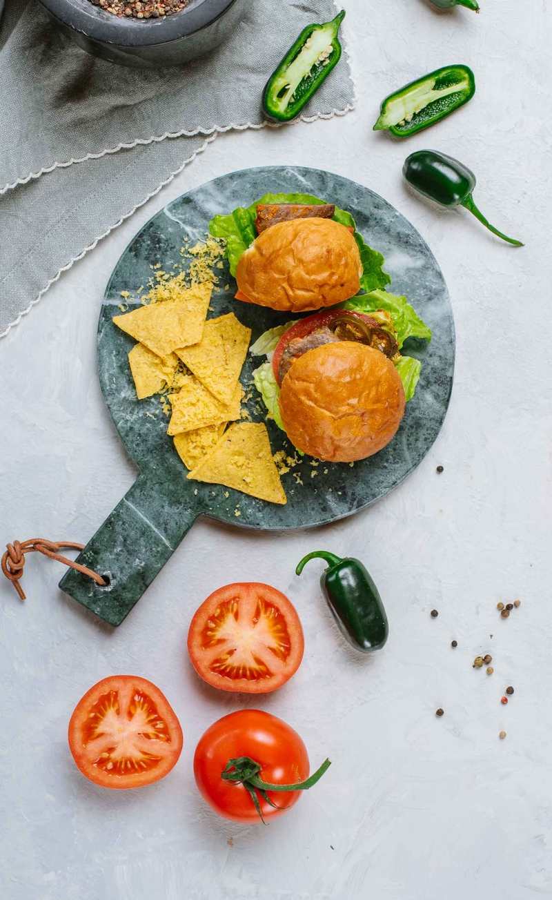 Wołowy burger w brioszce z dodatkiem chorizo, pomidora malinowego i jalapeno, kukurydziane nachos z serem cheddar