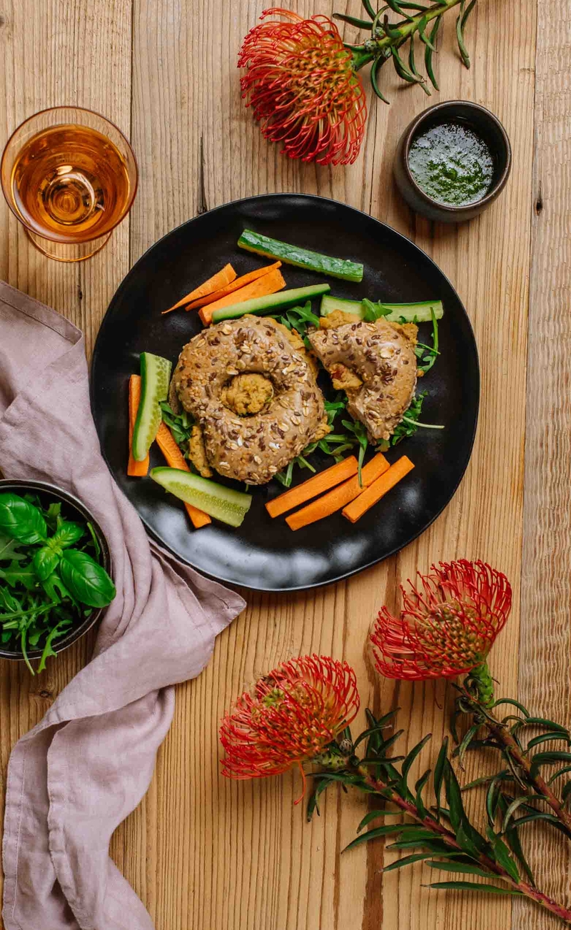 Bajgiel z bezjajeczną pastą z suszonymi pomidorami i rukolą, słupki warzyw, pesto bazyliowe
