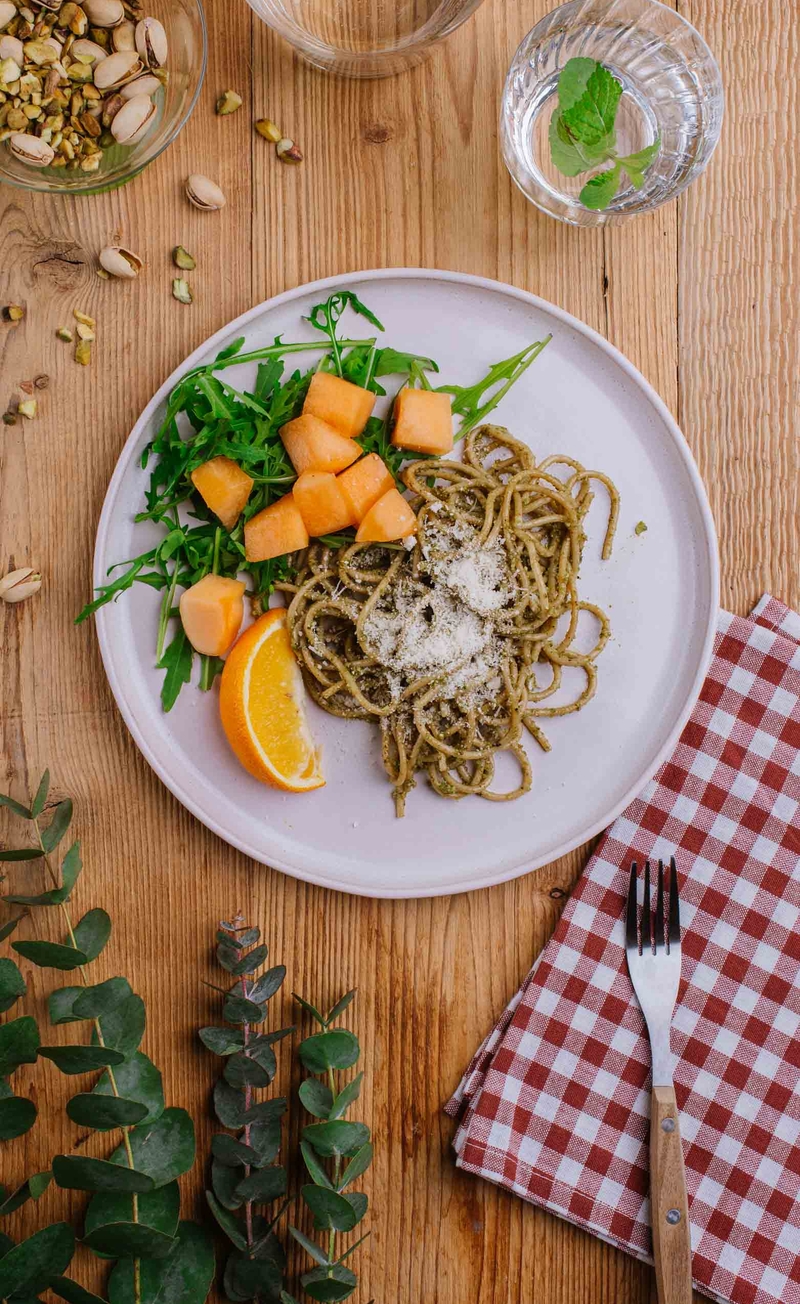 Makaron spaghetti pełnoziarniste z pesto pistacjowym, rukola z melonem, ćwiartka pomarańczy