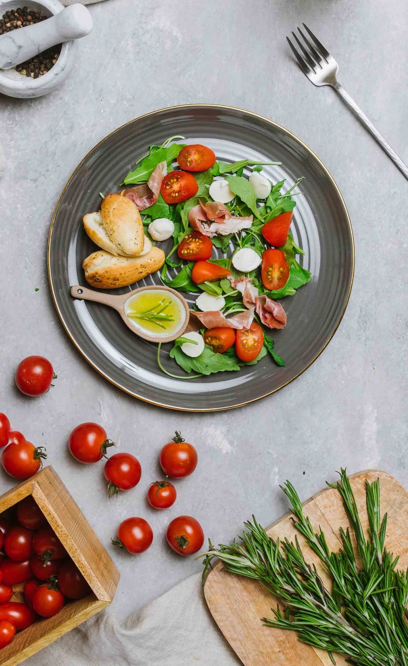 Sałatka z prosciutto di parma, mini mozzarellą, rukolą, pomidorkami, oliwa aromatyzowana rozmarynem, paluchy drożdżowe