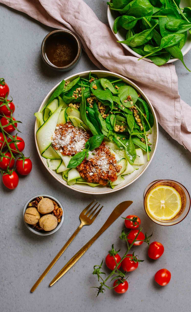 Keto spaghetti bolognese z warzywnym makaronem i parmezanem, liście szpinaku z orzechami włoskimi i sosem balsamicznym
