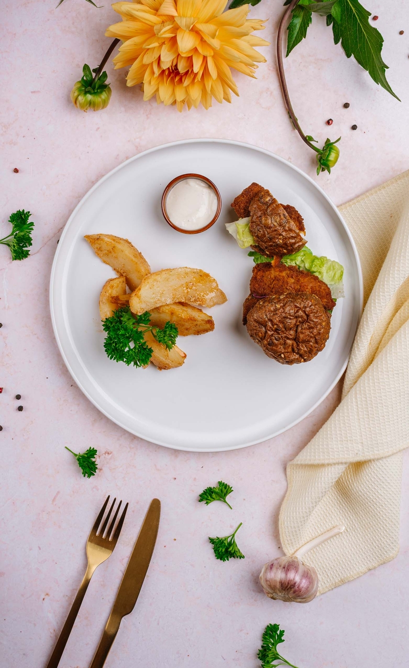 Proteinowy burger z nie-stripsami i marynowaną cebulką, łódeczki ziemniaczane, sos czosnkowy