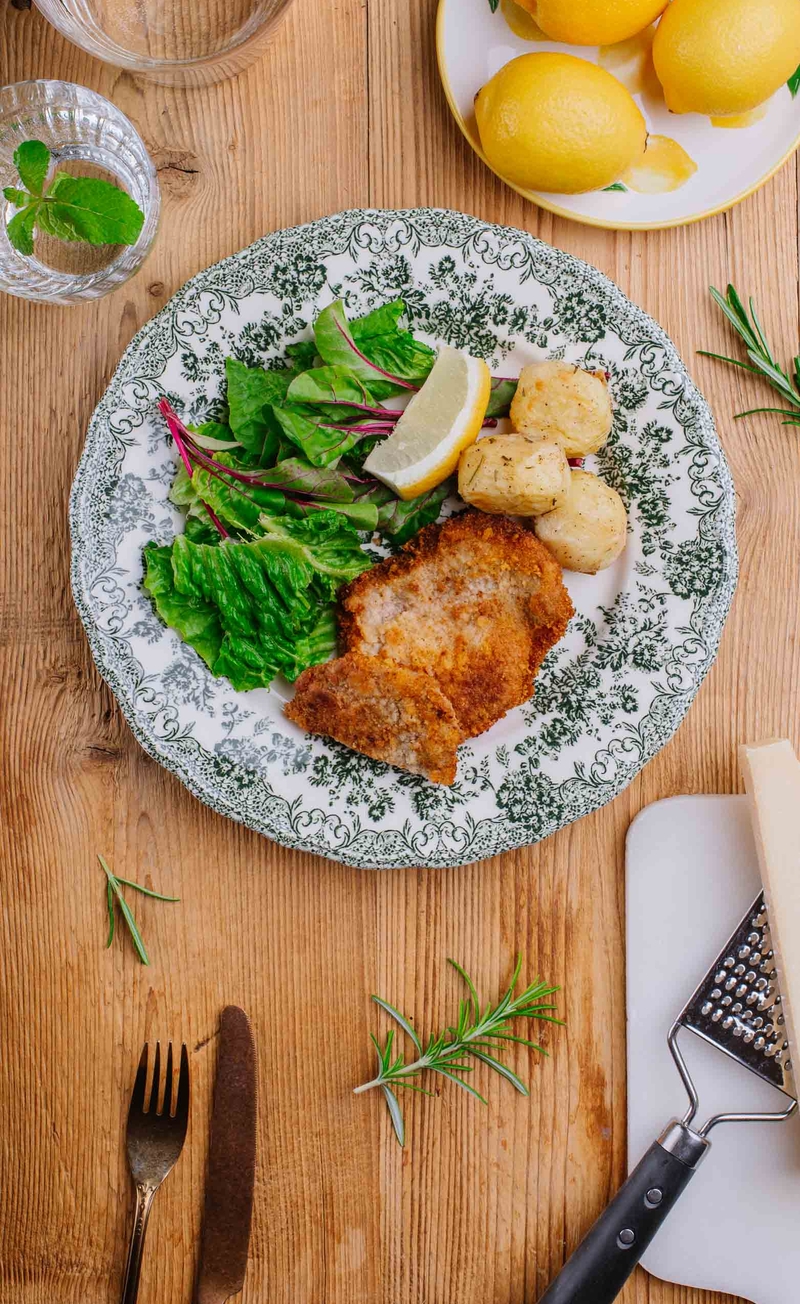 Cotoletta alla milanese - schab w parmezanowej panierce, pieczone ziemniaki z rozmarynem, sezonowe sałaty, ćwiartka cytryny