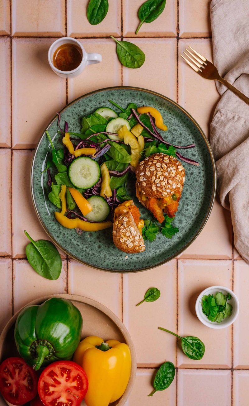 Burger z pikantnymi stripsami roślinnego qurczaka i mango mayo, sałatka ze szpinakiem i czerwoną kapustą, kolendra