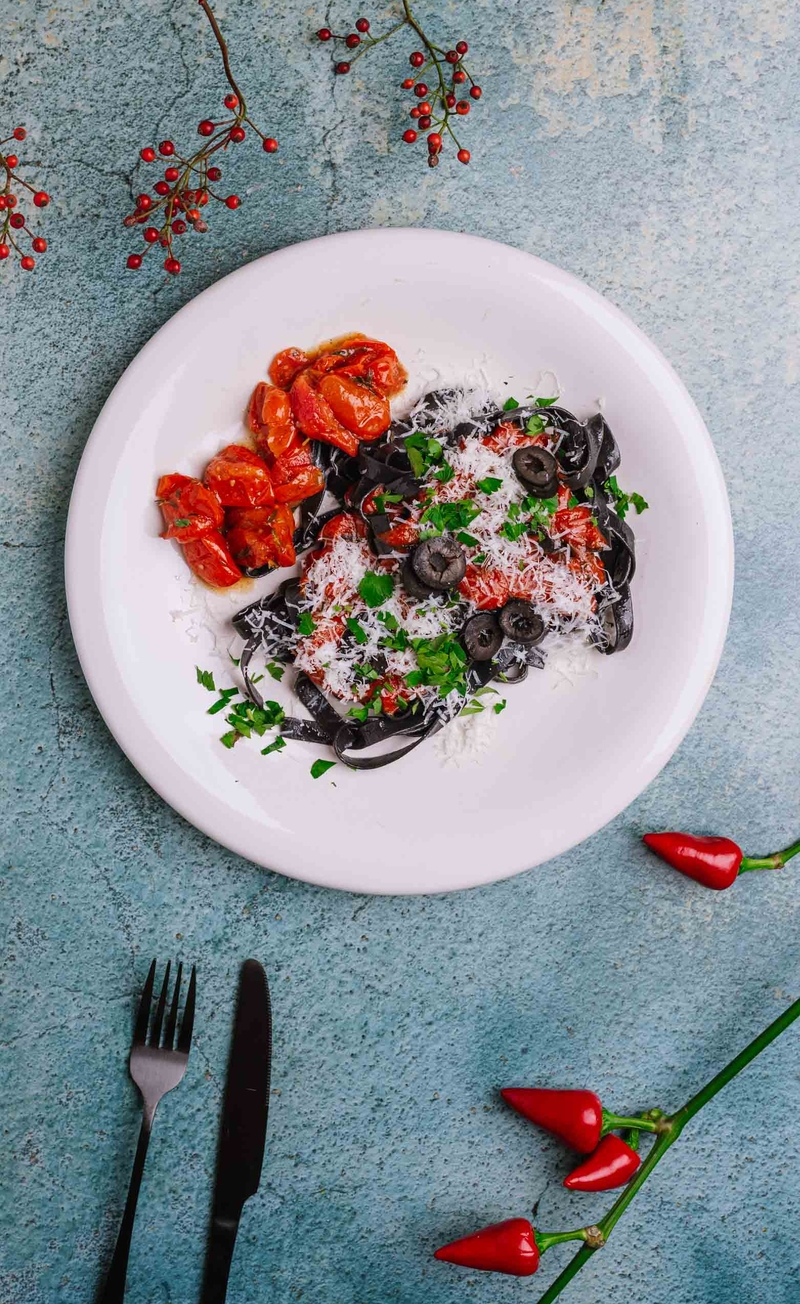 Czarne tagliatelle w sosie alla puttanesca z pieczonymi pomidorkami, oliwkami i tartym serem pecorino