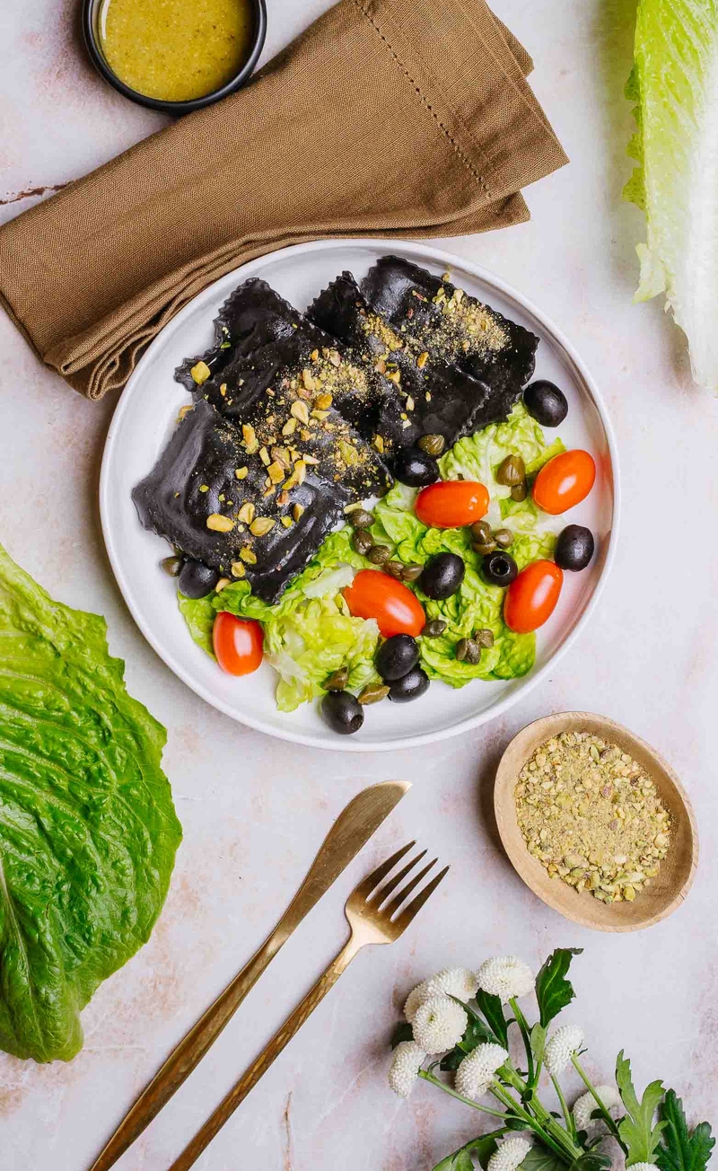 Czarne ravioli z krewetkami, pesto pistacjowe, sałata rzymska z pomidorkami, oliwkami i kaparami