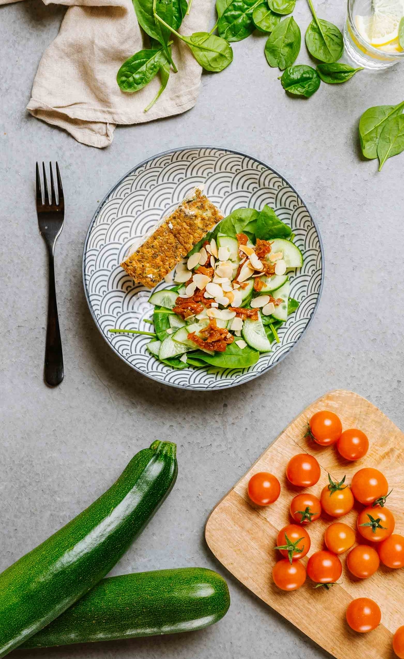 Keto fritatta z cukinią, boczkiem i greckim serem, świeże warzywa z migdałami i suszonymi pomidorami