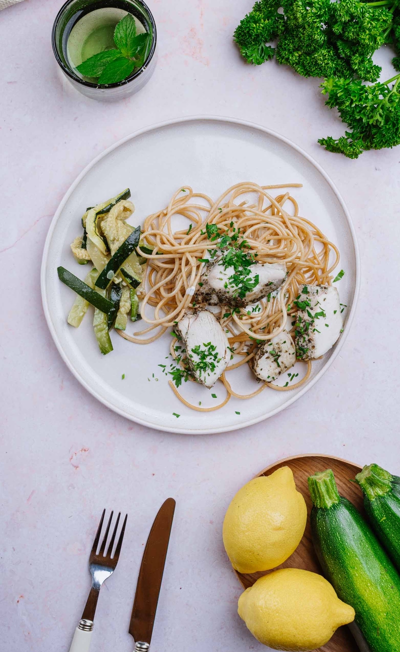 Plastry kurczaka w śmietanowym sosie ze skórką cytryny i natką pietruszki, pieczone słupki cukinii, pełnoziarniste spaghetti