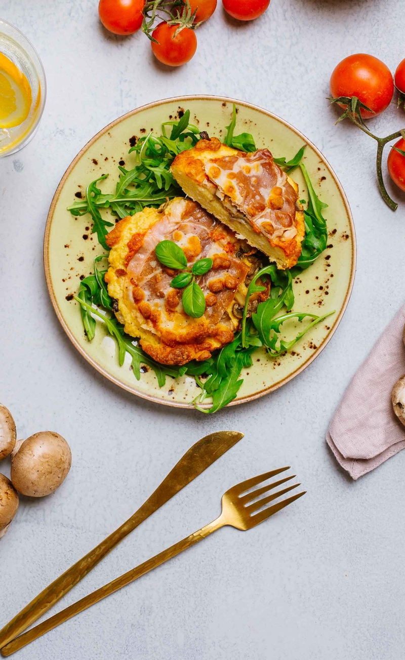 Pizza na spodzie z kalafiora z szynką parmeńską, mozzarellą, pieczarkami i rukolą