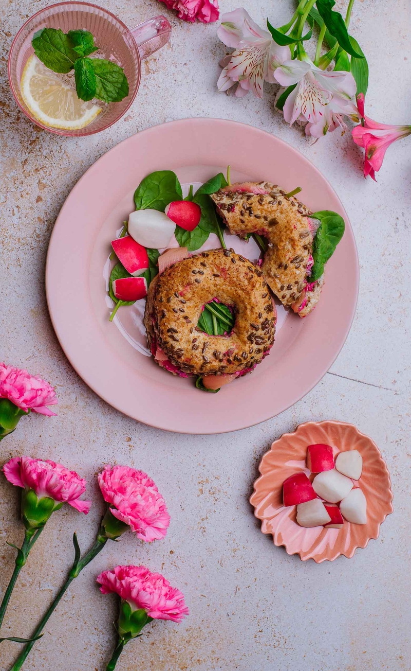 Bajgiel z różowym twarożkiem, łososiem i świeżym szpinakiem, świeże warzywa