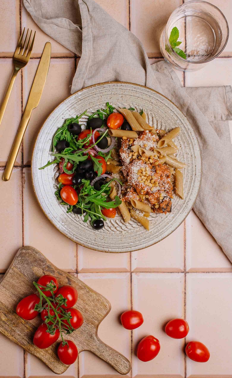 Sycylijska pasta alla norma z ricottą i bakłażanem, rukola z pomidorkami i oliwkami