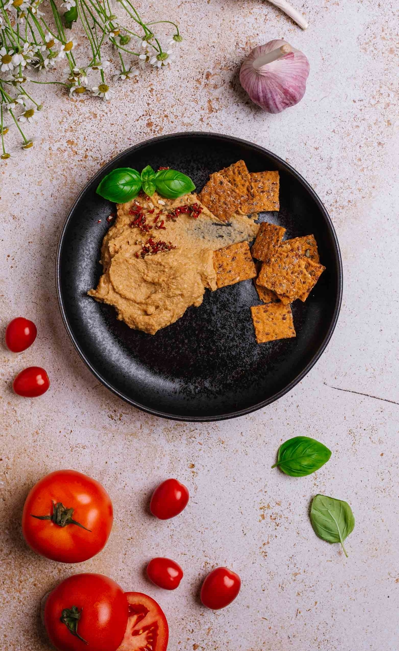 Hummus z pieczonym czosnkiem, krakersy żytnie z posypką pomidorowo-bazyliową
