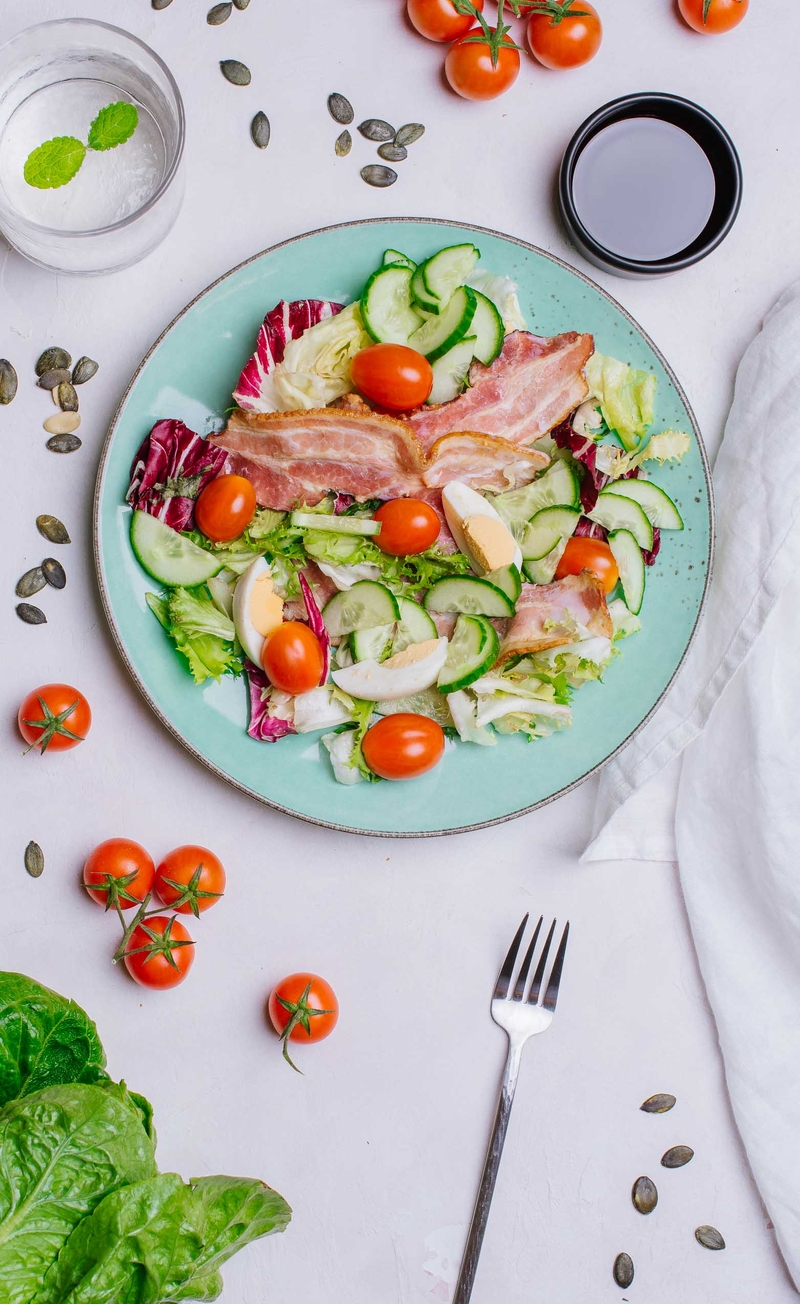 Keto sałatka śniadaniowa z jajkiem na twardo, chipsem z boczku, mixem sałat i ogórkiem, olej z pestek dyni