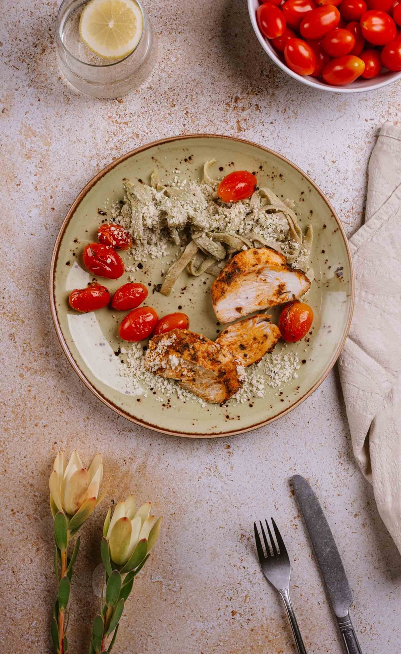 Pełnoziarniste tagliatelle z pesto bazyliowym, plastrami kurczaka i tartym parmezanem, pieczone pomidorki