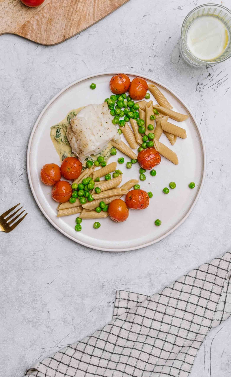Makaron pełnoziarnisty w sosie śmietanowym ze szpinakiem i dorszem, pieczone pomidorki z groszkiem