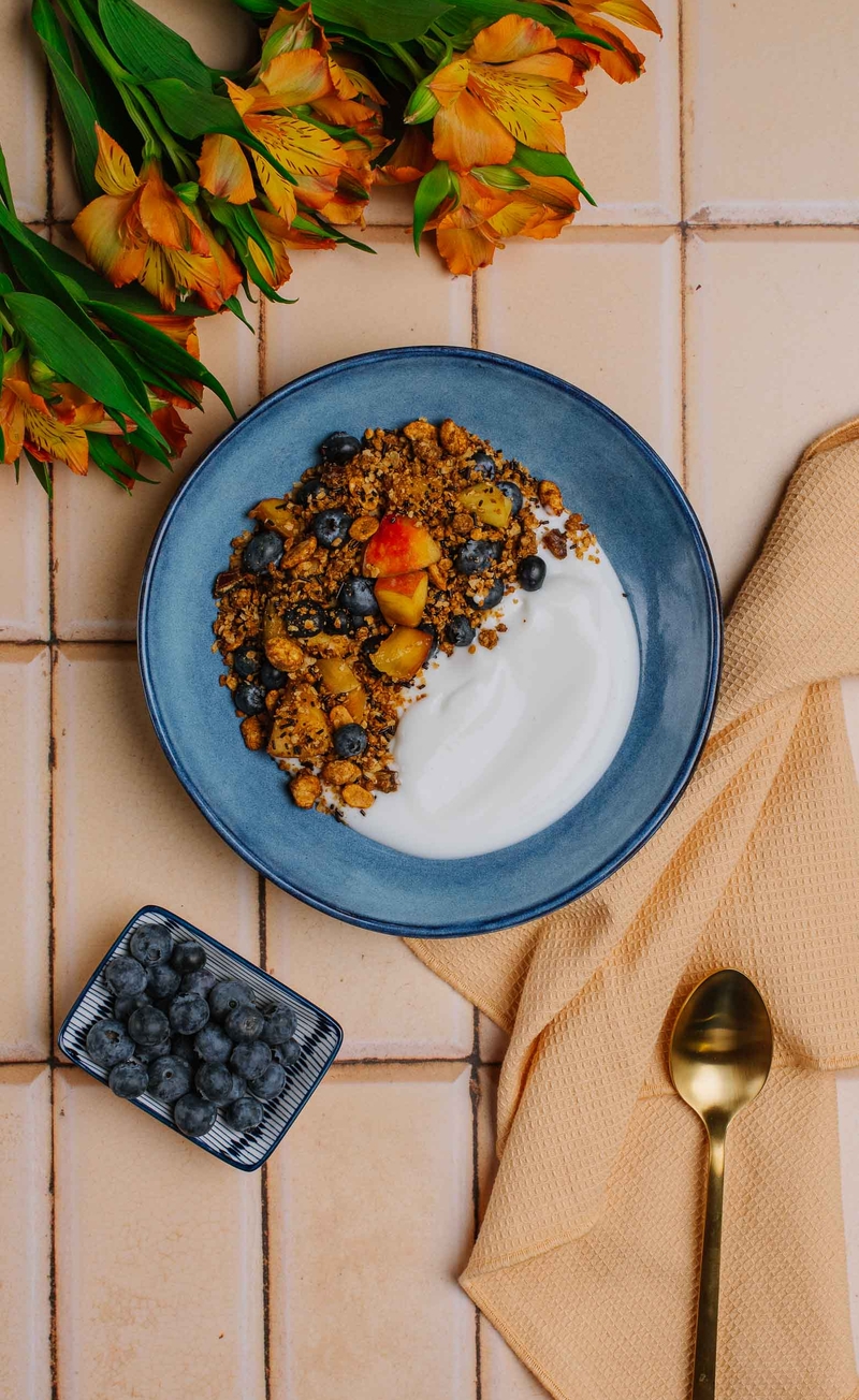 Granola snickers z karmelizowanymi orzeszkami ziemnymi, jogurt kokosowy, borówki, brzoskwinia