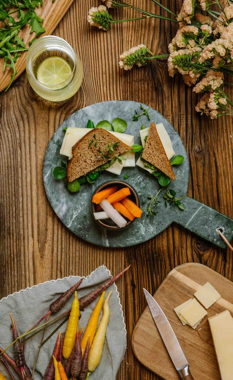Kanapka razowa z pesto z rukoli i pestek dyni, roszponką i serem edamskim, słupki warzyw