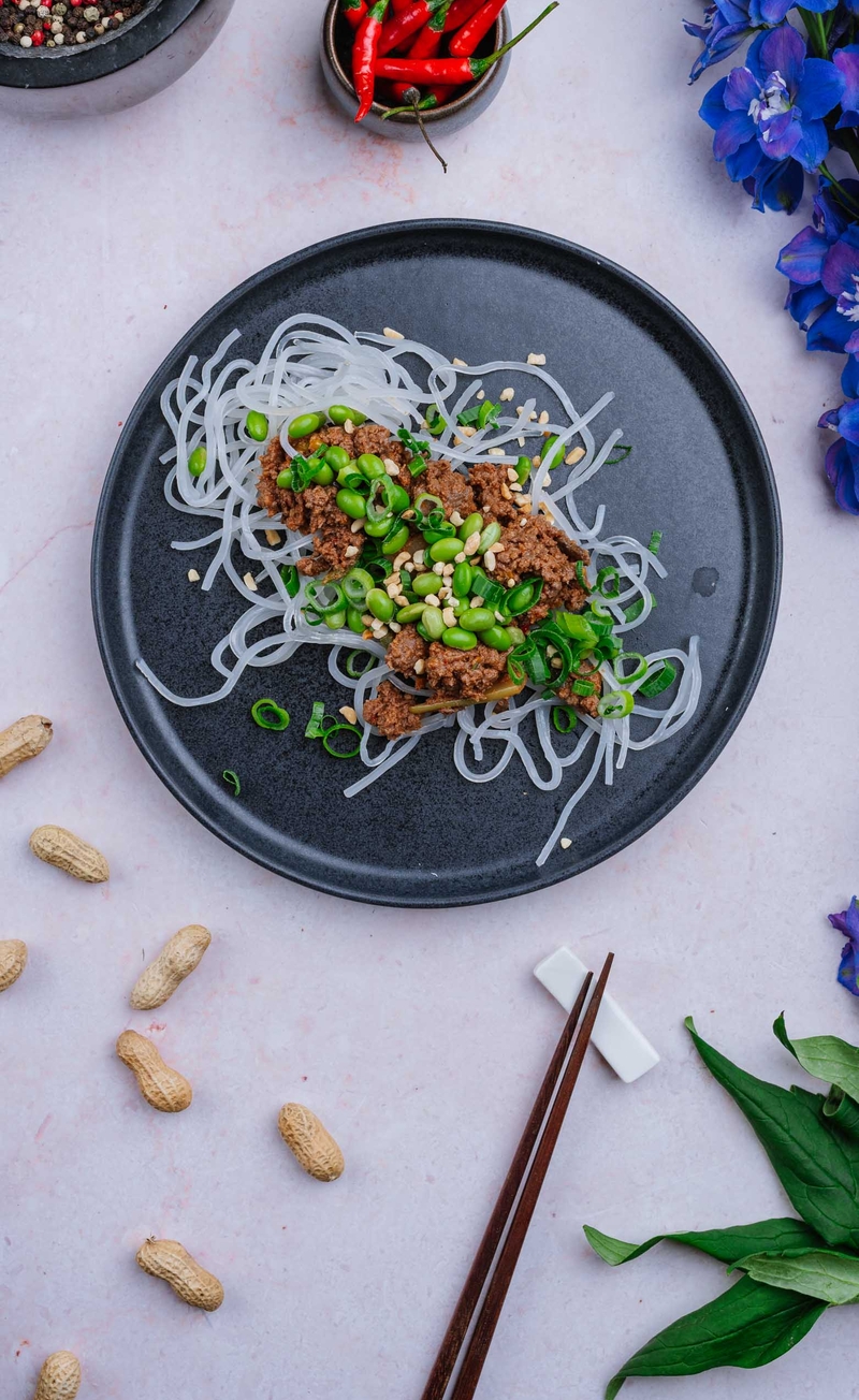 Mielona wołowina w kwaśno-pikantnym sosie z fasolką edamame, papryką, pędami bambusa i fistaszkami, makaron japchae